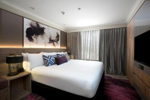 a bedroom with a large white bed and a television at Rydges South Bank Brisbane in Brisbane