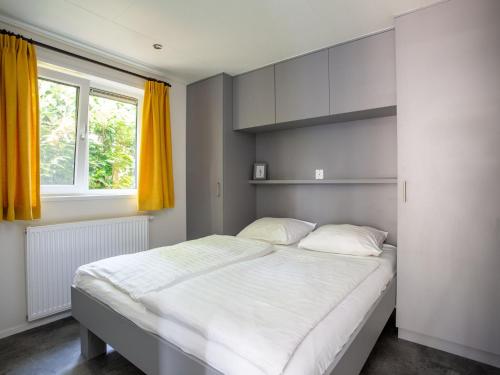 een slaapkamer met een groot wit bed en een raam bij Modern house with roof, located in a holiday park in Rhenen in Rhenen