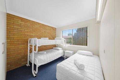 a bedroom with two bunk beds and a brick wall at Sundial Holiday Units in North Haven