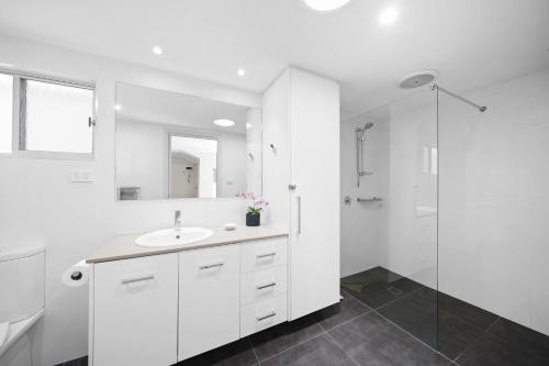 a white bathroom with a sink and a shower at Sundial Holiday Units in North Haven