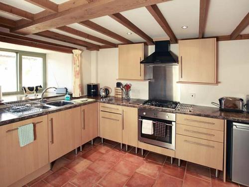 a kitchen with wooden cabinets and a stove top oven at Cow Byre Cottage in Pickering
