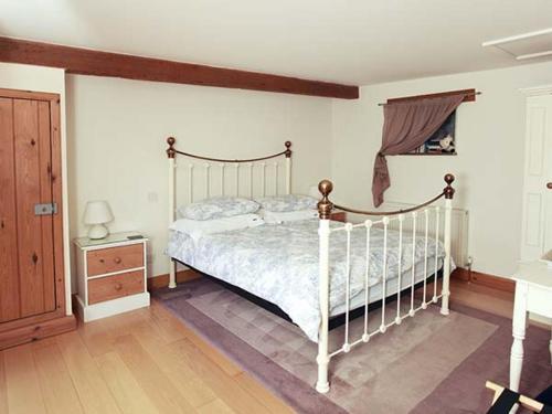 a bedroom with a white bed and a wooden floor at Cow Byre Cottage in Pickering