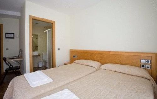 1 dormitorio con 2 camas y escritorio. en Amolls Restaurant i Habitacions, en Olot