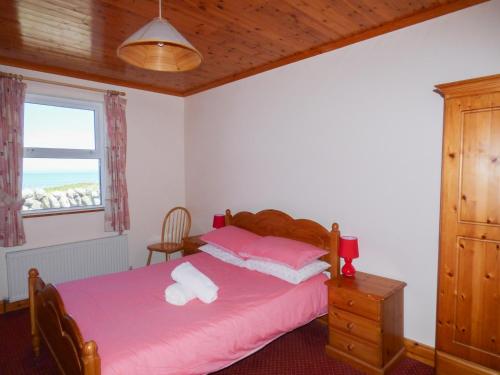 1 dormitorio con cama con sábanas rosas y ventana en Seaview Cottage, en Ballyvaughan
