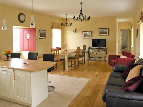 a living room with a couch and a dining room at Dolmen Cottage in Kilfenora