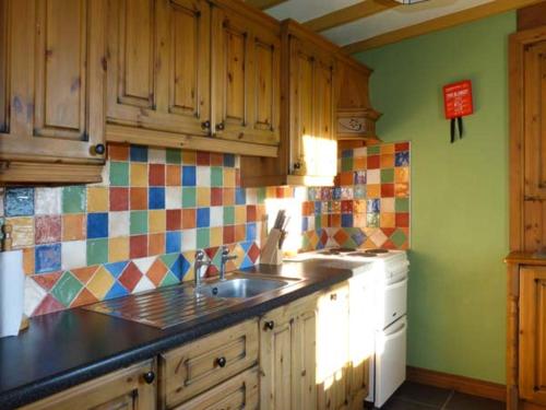 a kitchen with a sink and colorful tiles on the wall at Sugarbush in Eyeries