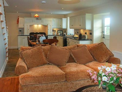 a living room with a brown couch and a kitchen at Nellie's Farmhouse in Bantry