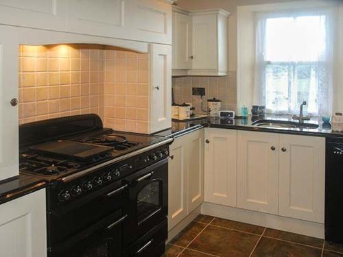 a kitchen with a black stove and white cabinets at Nellie's Farmhouse in Bantry