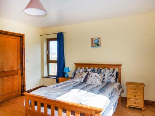 una camera con letto in legno e finestra di 6 Strand Cottages a Doogort