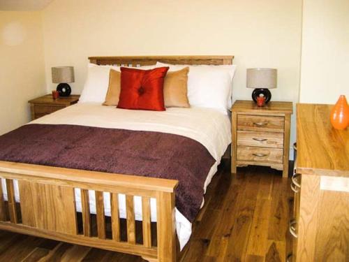 sypialnia z dużym łóżkiem z czerwonymi poduszkami w obiekcie Watch House Cottage w mieście Knights Town