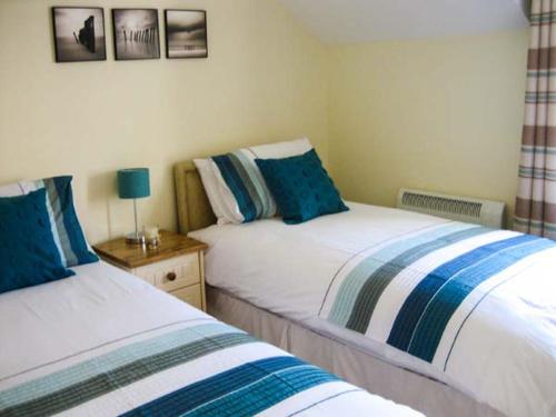 a bedroom with two beds with blue and white sheets at Watch House Cottage in Knights Town