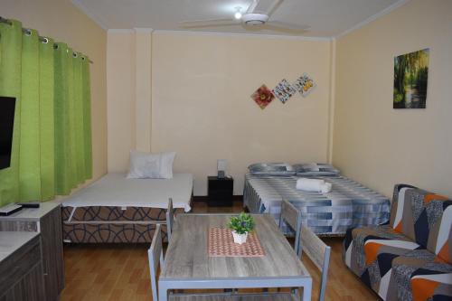 a room with two beds and a table and a tv at Treetops Studios Valencia,Dumaguete in Valencia