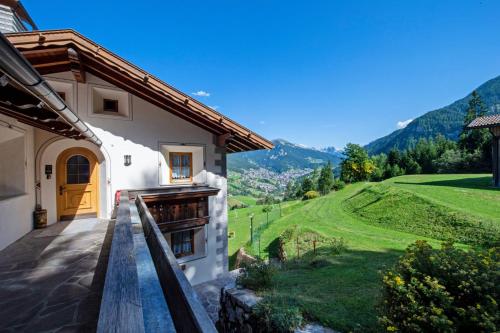a house with a balcony with a view of a green field at Chalet Alpina in Ortisei