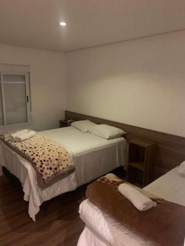 a hotel room with two beds and a table at Hotel Palmeiras in Santana do Livramento