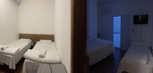 a room with three beds and a window at Hotel Palmeiras in Santana do Livramento
