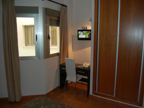 a room with a desk with a computer and a television at Hotel Almoradi in Almoradí