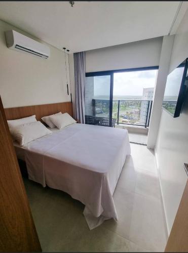 a bedroom with a white bed and a large window at Salinas Premiun Resort 703 in Salinópolis