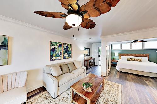 uma sala de estar com um sofá e uma ventoinha de tecto em Hale Ono Loa 210 em Kahana