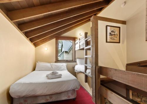 a small attic bedroom with a bed and a book shelf at Seadog in Dinner Plain