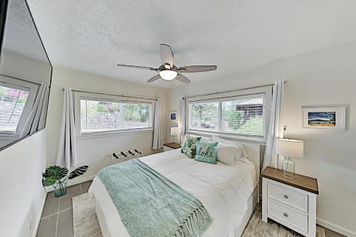 a bedroom with a bed and two windows at Nahenahe Cottage in Wailea