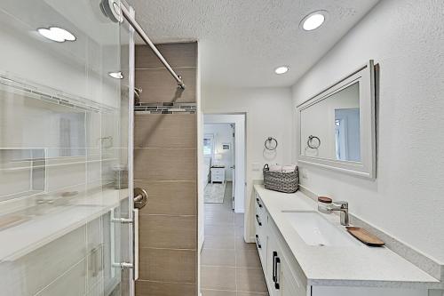 a white bathroom with a shower and a sink at Nahenahe Cottage in Wailea