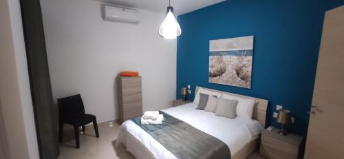 1 dormitorio con 1 cama con pared azul en Searenity, en Marsaxlokk