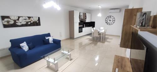 a living room with a blue couch and a kitchen at Searenity in Marsaxlokk