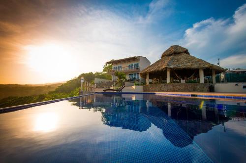 uma piscina de resort com telhado de palha em Hotel Los Mangos El Salvador em El Cuco