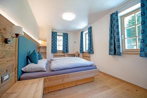 een slaapkamer met een bed met blauwe gordijnen bij Apartments Alpen Domus in Selva di Val Gardena