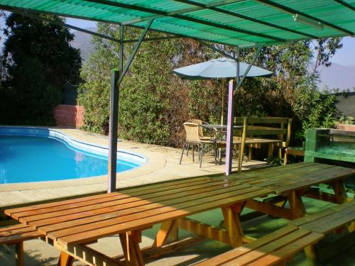 a picnic table with an umbrella next to a pool at La Gran Casona de Olmue in Olmué