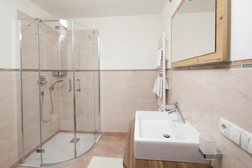 La salle de bains est pourvue d'une douche et d'un lavabo blanc. dans l'établissement Apartments Mirandula, à Ortisei