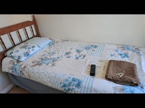 a bed with a book and a remote control on it at Tiny Single shared bathroom Room ssbyr in Hayes