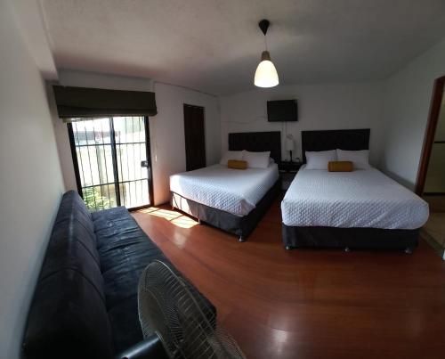 a living room with two beds and a couch at Global Airport Inn FREE Shuttle in Guatemala