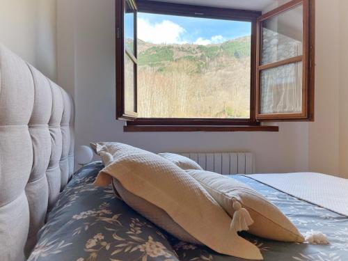 Una cama con una manta y una ventana en Apartamento Valle de Alba en Benasque