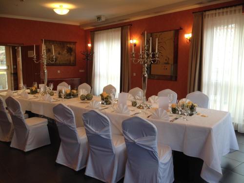 a room with a long table with white tables and chairs at Waldhotel Rheinbach in Rheinbach