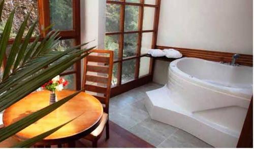 a bathroom with a bath tub and a table and a table sidx sidx at Casa del Sol Machupicchu in Machu Picchu