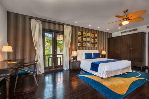 1 dormitorio con cama, escritorio y piano en Da Nang Paradise Center My Khe Beach Resort & Spa en Da Nang