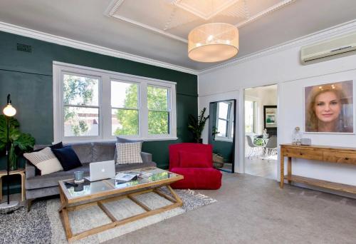 a living room with a couch and a red chair at The Baylis Boutique Apartments in Wagga Wagga