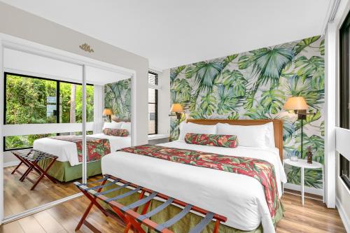 two beds in a room with a tropical wallpaper at Casa Tropical Kona in Kailua-Kona