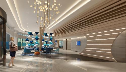 a woman walking through a lobby with a chandelier at Holiday Inn Express Yibin by IHG in Yibin