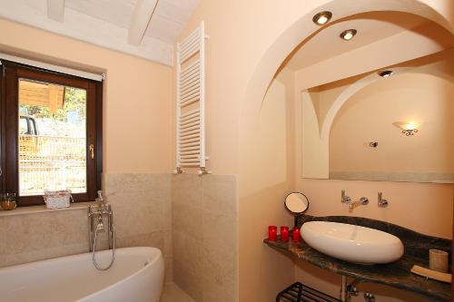 a bathroom with a sink and a tub and a mirror at Le Petit Palais Villa in Plesio