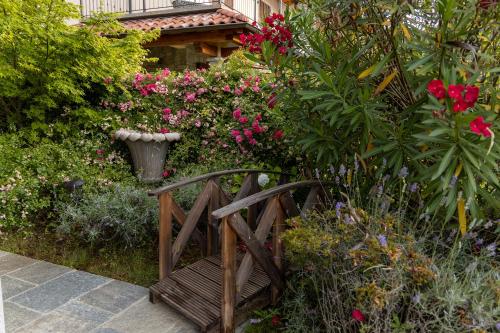 a wooden bench in a garden with flowers at Le Petit Palais Villa in Plesio