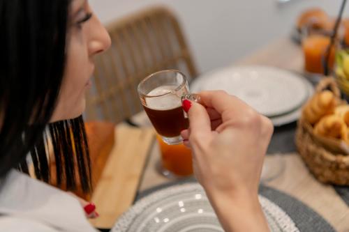 a woman holding a glass of beer at a table at SyRose Suites in Ermoupoli
