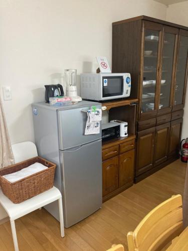 a kitchen with a refrigerator and a microwave at 森のカフェ in Beppu