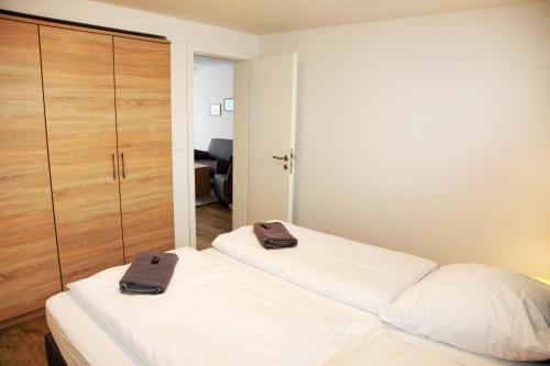 a bedroom with two white beds and a closet at Ferienwohnungen Strandglück in Norddeich