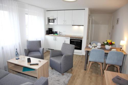 a living room with a table and chairs and a kitchen at Ferienwohnungen Strandglück in Norddeich
