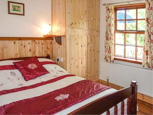 a bedroom with a large bed with red and white sheets at Hawthorn Farm Cottage in Curry