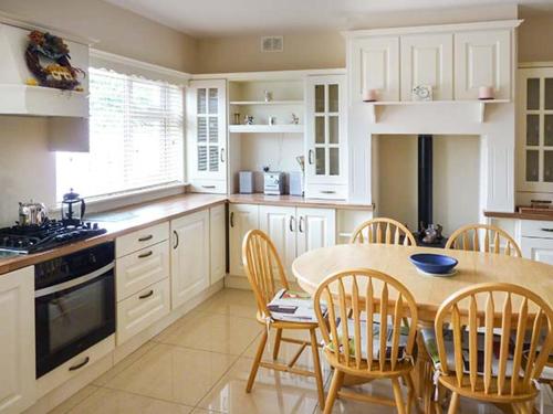 a kitchen with a table and chairs and a kitchen with white cabinets at Lovers' Lodge in Kilkenny