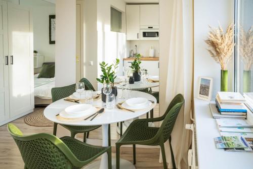 comedor con mesa blanca y sillas verdes en Čia gera studio, en Anykščiai