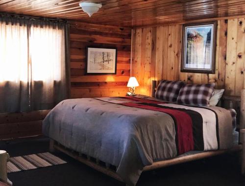 a bedroom with a bed in a log cabin at Elkhorn Lodge in Chama